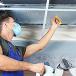 Masked person fixing ceiling 